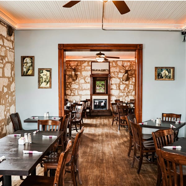 Interior of Silver Creek Beer Garden & Grille with wooden tables, chairs, and stone walls.