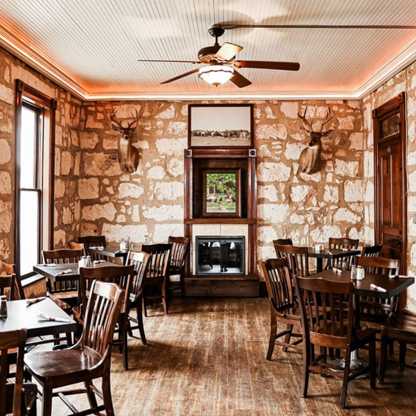 Rustic dining room at Silver Creek Beer Garden & Grille with stone walls, wooden tables, and deer mounts.