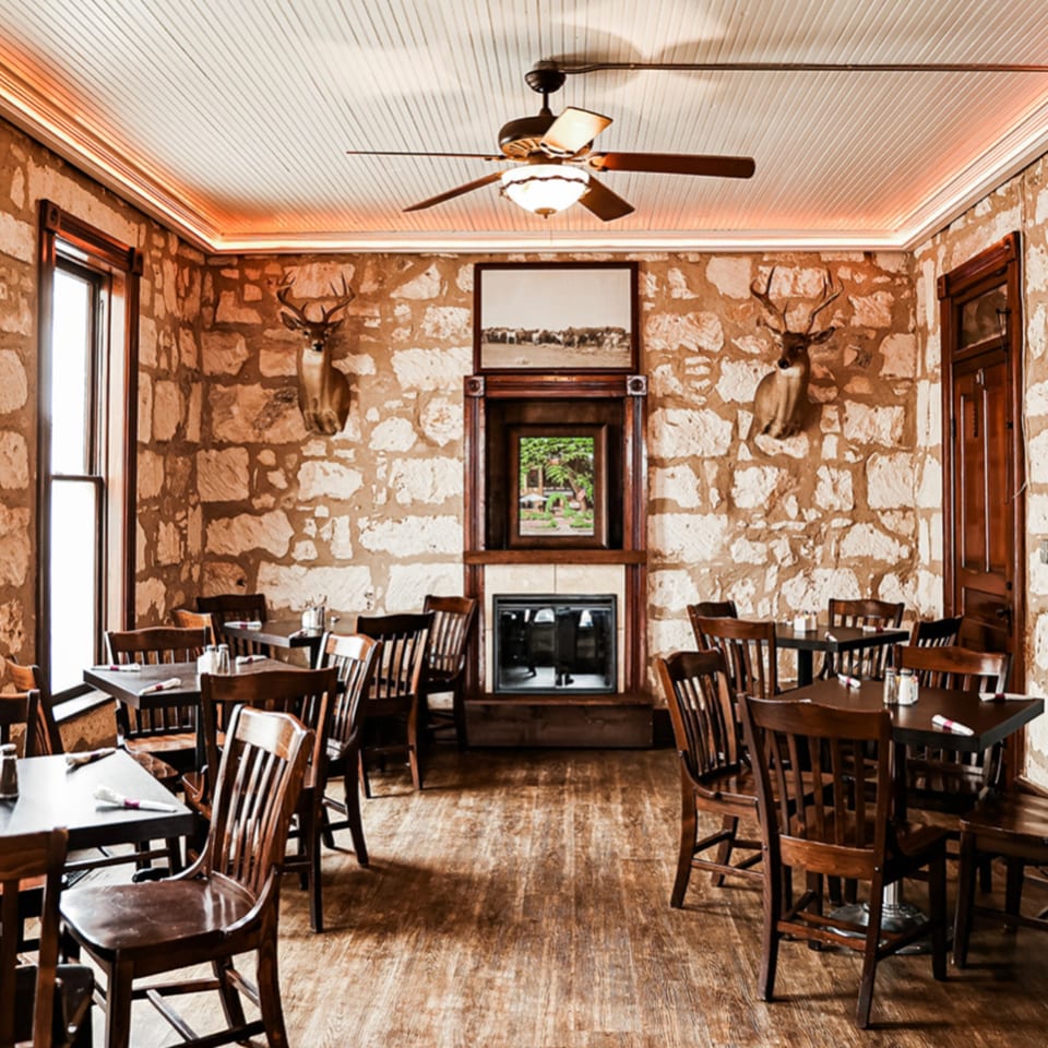 Rustic dining room at Silver Creek Beer Garden & Grille with stone walls, wooden tables, and deer mounts.
