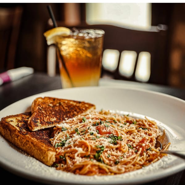 Spaghetti with tomato sauce, parmesan, and parsley, served with grilled toast and a drink.