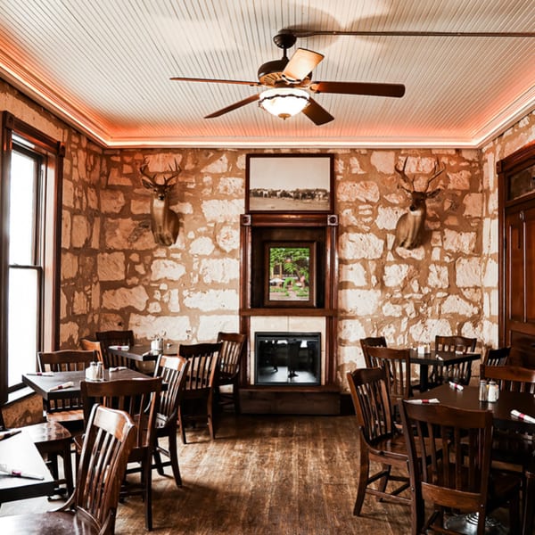 Rustic dining room at Silver Creek Beer Garden & Grille with stone walls, wooden tables, and deer mounts.
