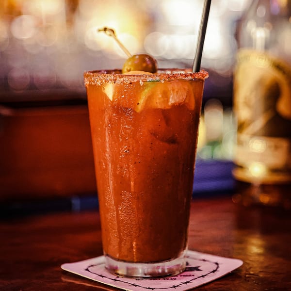A Bloody Mary cocktail with a salted rim, olive, and lime, on a coaster at Silver Creek Beer Garden & Grille.